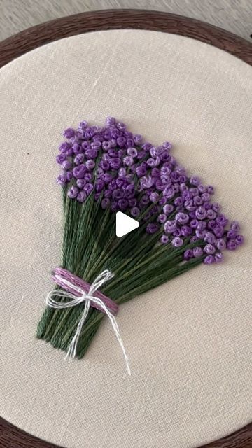 a bunch of purple flowers sitting on top of a white cloth covered table next to a wooden frame