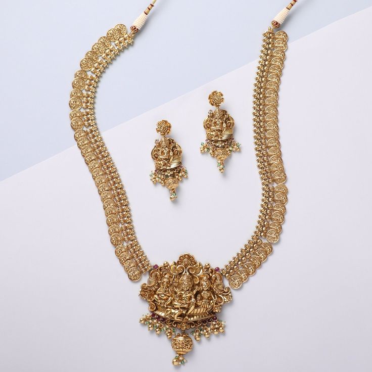 Description Infuse a classic twist to your festive look with the Mandira family's nakshi coin temple necklace. Embellished with nakshi motifs throughout, this 925 hallmark silver necklace portrays a detailed idol of Lord Shiva, Lord Ganesha, and Lord Kartikeya sitting together in a blessing posture. The necklace is completed with lustrous antique gold-tone plating. Elevate your festive appearance by pairing this necklace with other nakshi jewelry accessories. Product Information Materials used: 22k Gold Chandbali Temple Necklace For Celebration, 22k Gold Temple Necklace For Navratri Celebration, 22k Gold Temple Necklace For Celebrations, Chandbali Style, 22k Gold Temple Necklace With Chandbali Shape For Celebration, 22k Gold Jewelry For Puja, 22k Gold Jewelry Sets For Puja And Festive Occasions, 22k Gold Chandbali Necklace With Cutdana, 22k Gold Temple Necklace With Tilla For Puja, Meenakari Pendant Temple Necklace For Puja