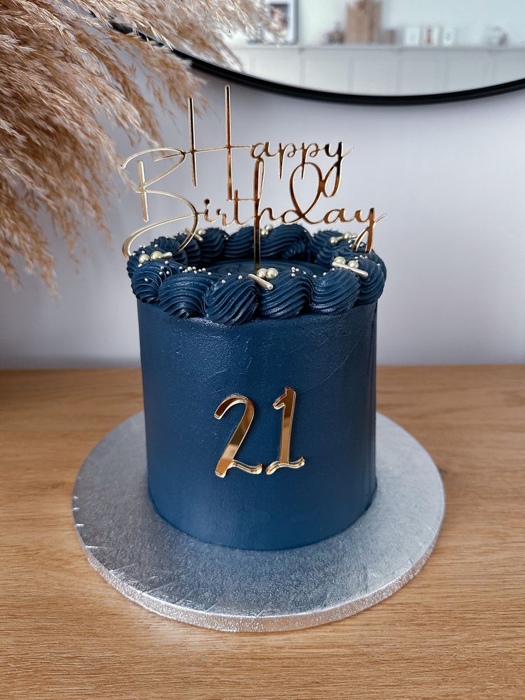 a birthday cake with blue frosting and gold numbers on top is sitting on a table