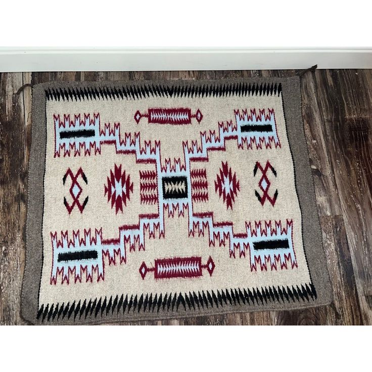 an old navajo rug is laying on the floor in front of a wooden flooring