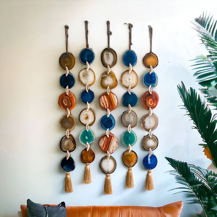 a wall hanging made out of different colored discs and tassels on a white wall