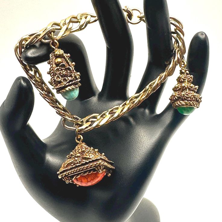 This is a vintage Etruscan Revival charm bracelet made from a thick, beautiful shining double link gold tone bracelet with three chunky ornate fob type charms. The charms have cabochon glass stones in varying colors and shapes. The first pyrimid shaped charm has a turquoise glass cabochon charm that reminds me of a robins egg or the sky. The middle charm is larger and is an orange oval egg shaped cabochon inside of a lovely ornate fob. The third is an ornate charm holding a marbled green glass c Vintage Etruscan Jewelry, Collectible Vintage Charm Costume Bracelets, Vintage Jeweled Bracelets For Collectible, Handmade Vintage Chain Bracelet, Vintage Green Jubilee Bracelet, Charm Bracelet Vintage, Vintage Jewelry Antique, Vintage Charm Bracelet, Jewelry Antique