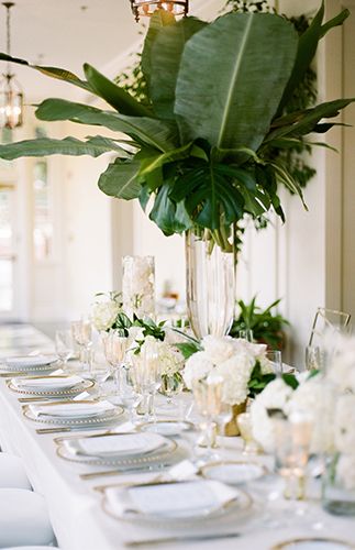 a long table is set with white flowers and greenery for an elegant wedding reception