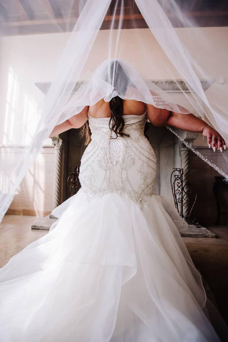 a woman in a wedding dress standing under a veil