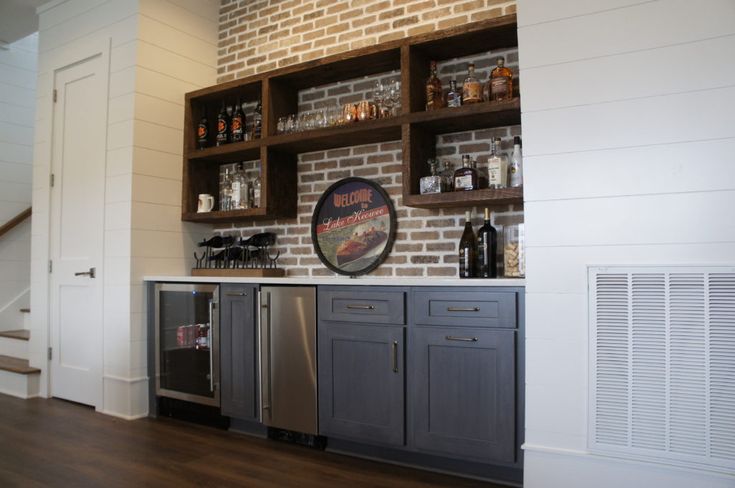 a brick wall in a home bar with stainless steel appliances and built - in shelving