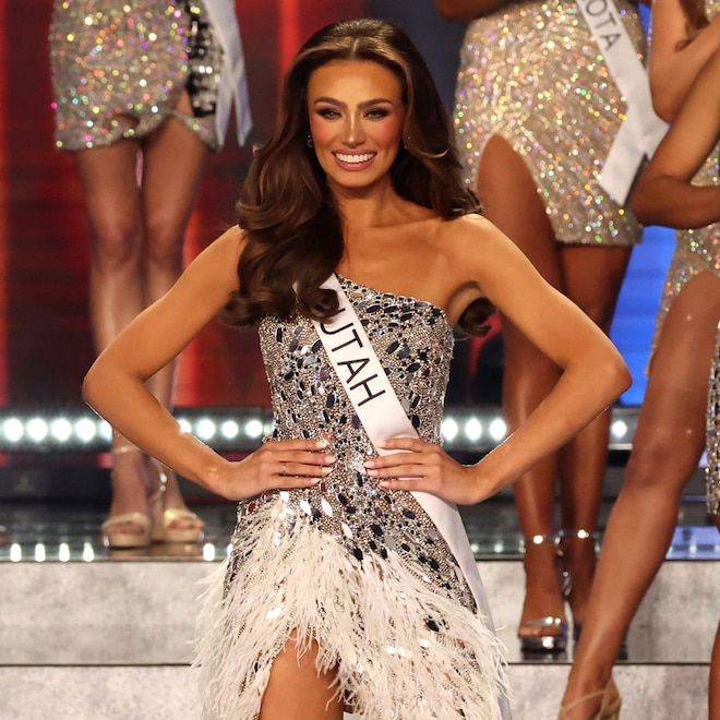 a woman in a silver and black dress standing next to another woman wearing a tiara