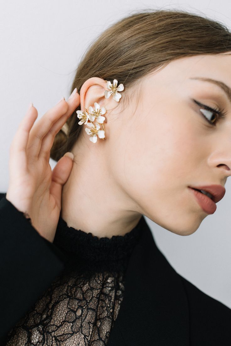 a woman wearing an ear cuff with flowers on it