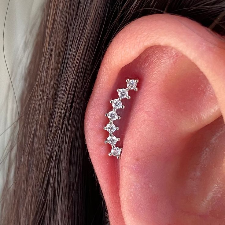 a woman's ear with three small white diamonds on the middle part of it