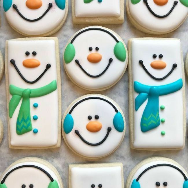 decorated cookies with frosting and icing snowmen are arranged on a sheet of paper