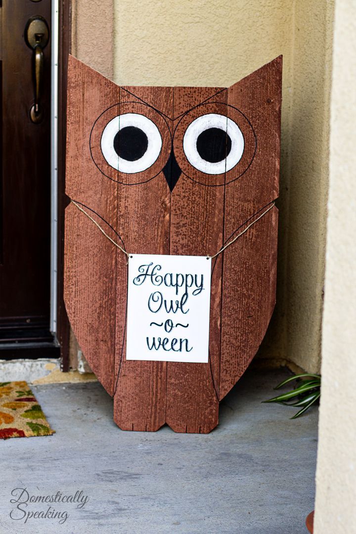 an owl made out of wood is sitting on the front porch with a sign that says happy owl o'ween