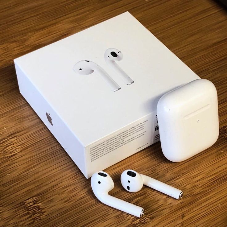 an apple box with two earphones and one charging unit on the floor next to it