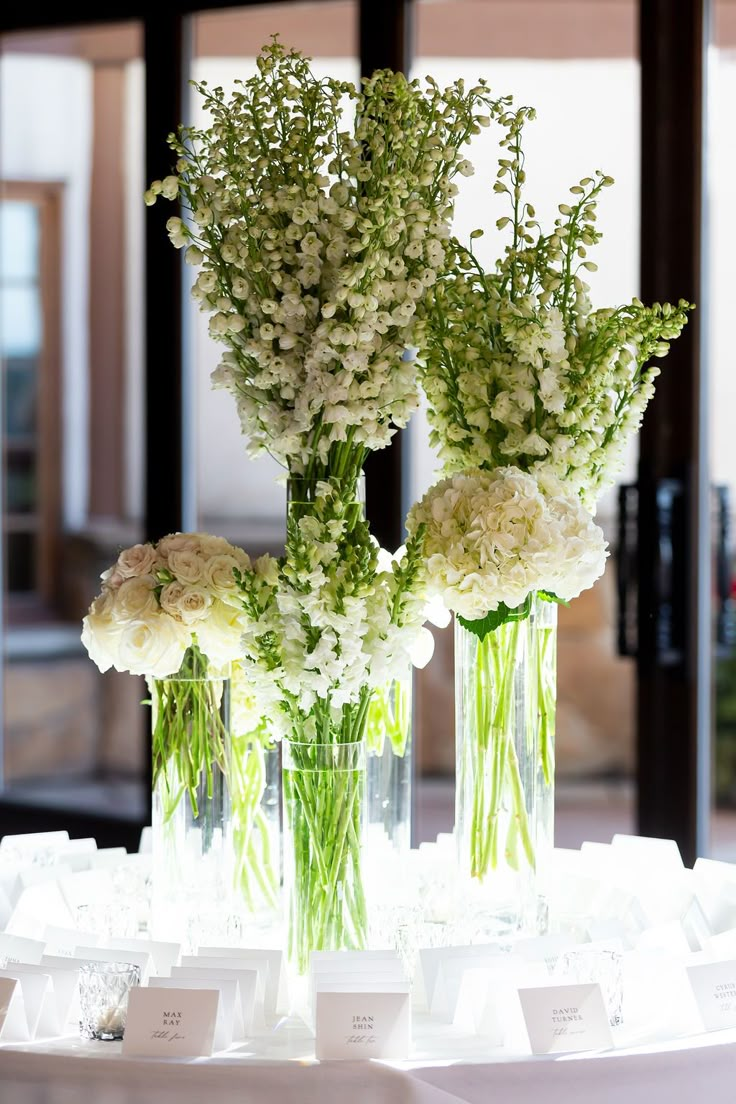 three vases filled with white flowers on top of a table