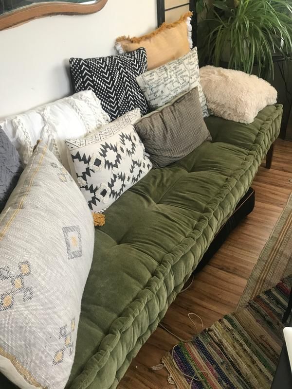 a green couch with lots of pillows on it