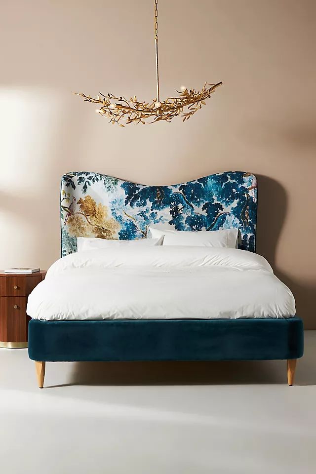 a bed with blue velvet headboard and white sheets