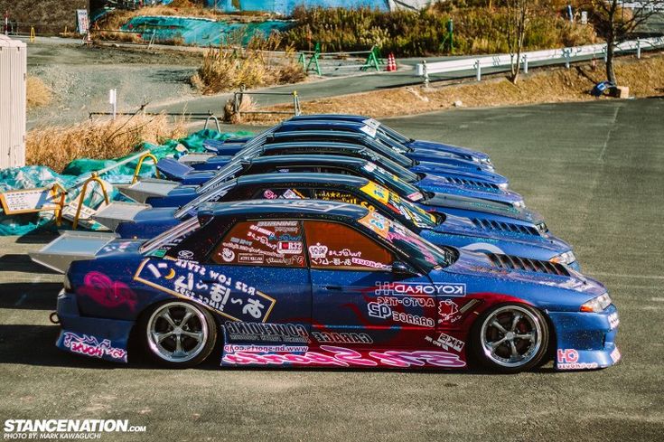 a row of race cars parked next to each other in a parking lot with graffiti on them