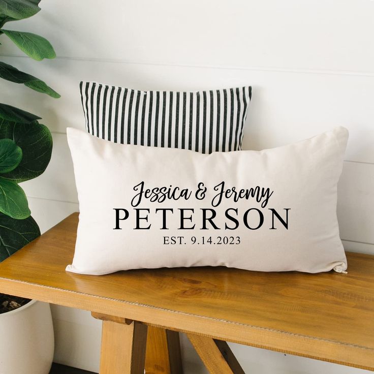 a personalized pillow sitting on top of a wooden bench next to a potted plant