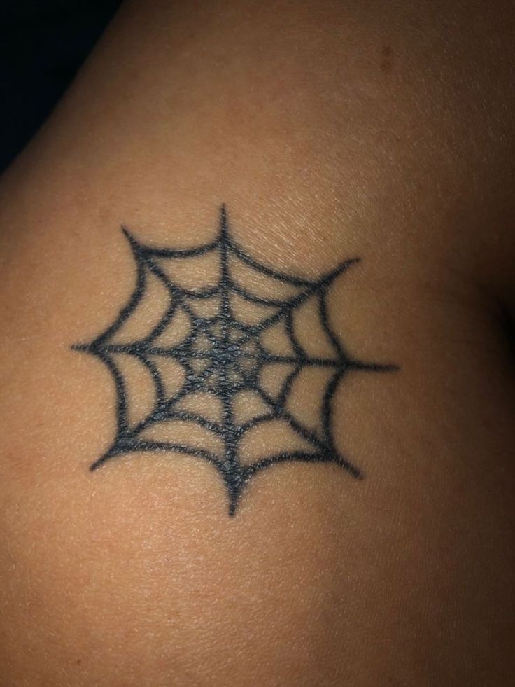 a spider web tattoo on the back of a woman's shoulder