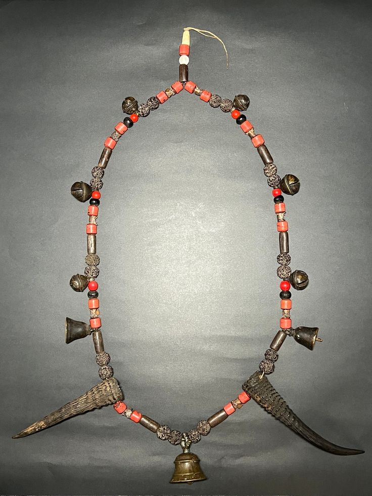 This Interesting and beautiful Old Primitive Shaman Metal Chain holy spiritual Necklace is from Western Nepal (Jumla) with: - Bronze Bells - Old Red Glass Beads - Rudraksha Beads - Seashell Beads - Cylindrical Metal Beads - Snake Bone - Wild Mountain Goat Horns - Beautiful Bronze Bell Centerpiece Shamans would wear necklaces like these when performing rituals or ceremonies. Collector and museum quality piece. Measurements: Length - 27 inches Weight - 704 grams * Colors may vary slightly in perso Shaman Necklace Bones, Traditional Jewelry With Wooden Beads For Blessing, Spiritual Jewelry For Traditional Ceremonies And Festivals, Traditional Hand-strung Necklaces For Blessing, Traditional Hand-strung Necklace For Ceremonial Occasions, Traditional Beaded Jewelry For Blessing, Adjustable Necklaces For Blessings And Festivals, Adjustable Necklace For Blessings And Festivals, Unique Hand-strung Necklaces For Rituals