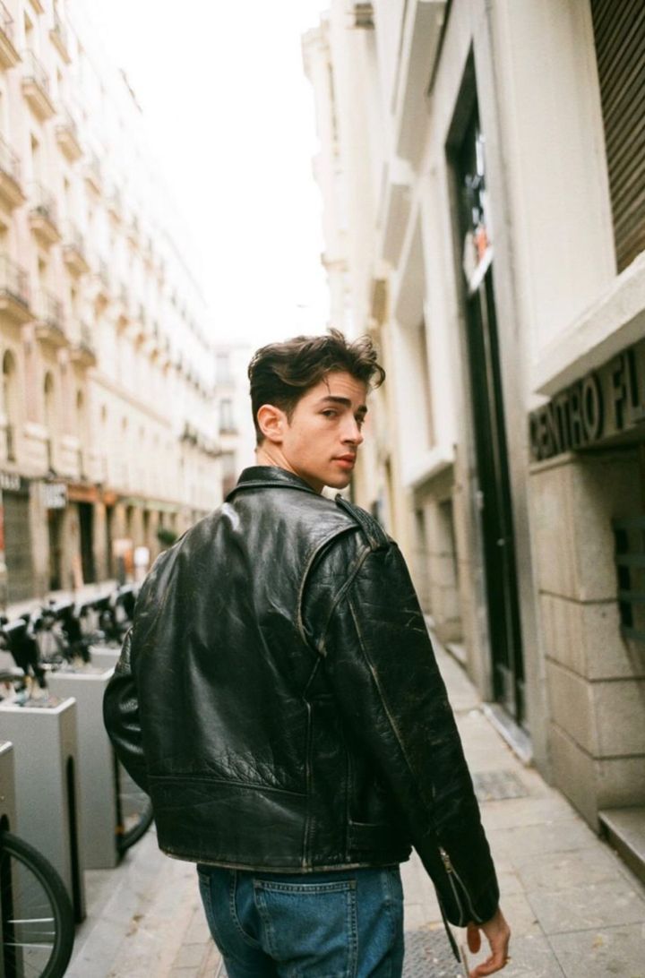 a man walking down the street in a leather jacket