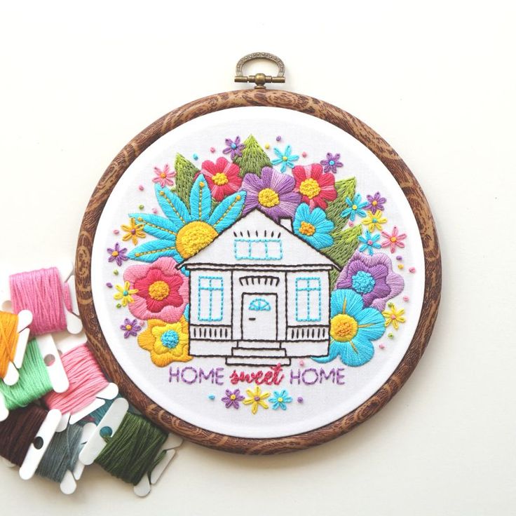 a embroidery kit with flowers and a house in the center, surrounded by small pieces of thread