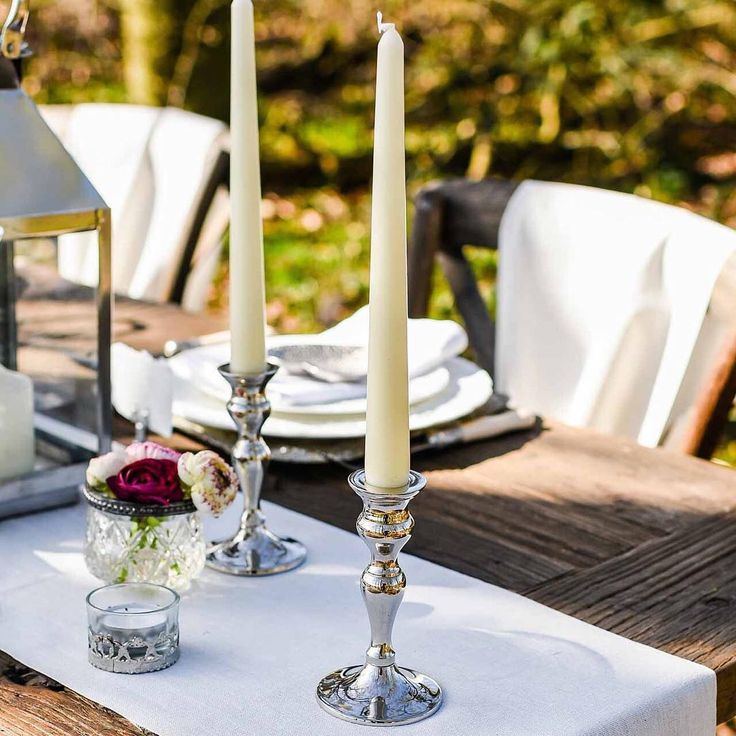 the table is set with candles and flowers on it for an outdoor dinner or party