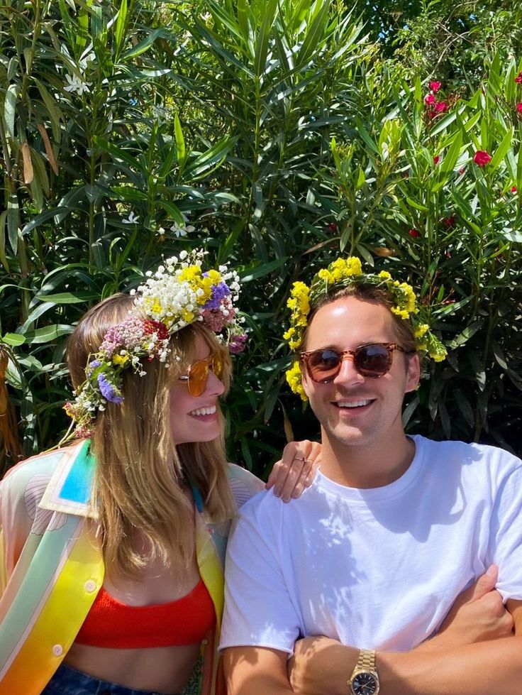 two people sitting next to each other wearing flower crowns