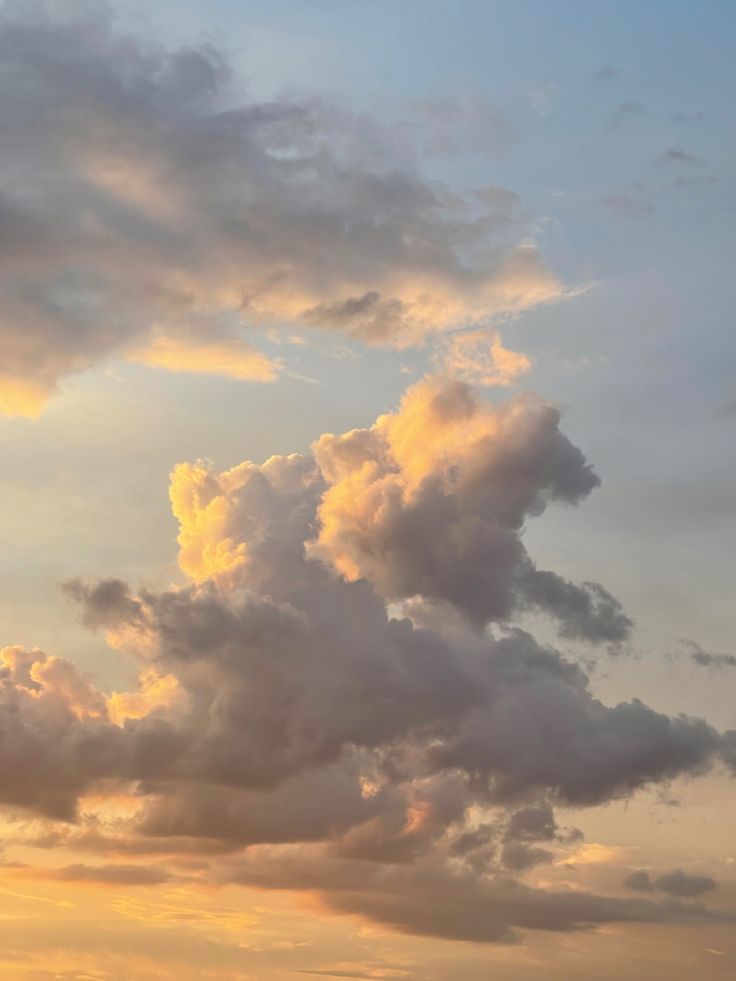 an airplane is flying in the sky with some clouds above it and another plane on the ground