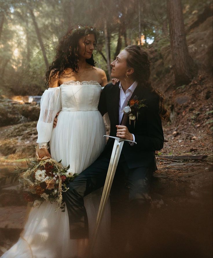 a man and woman dressed in wedding attire sitting next to each other on the ground