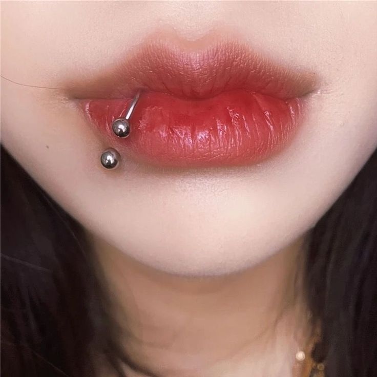 a close up of a woman's lips with piercings on her lip and nose ring