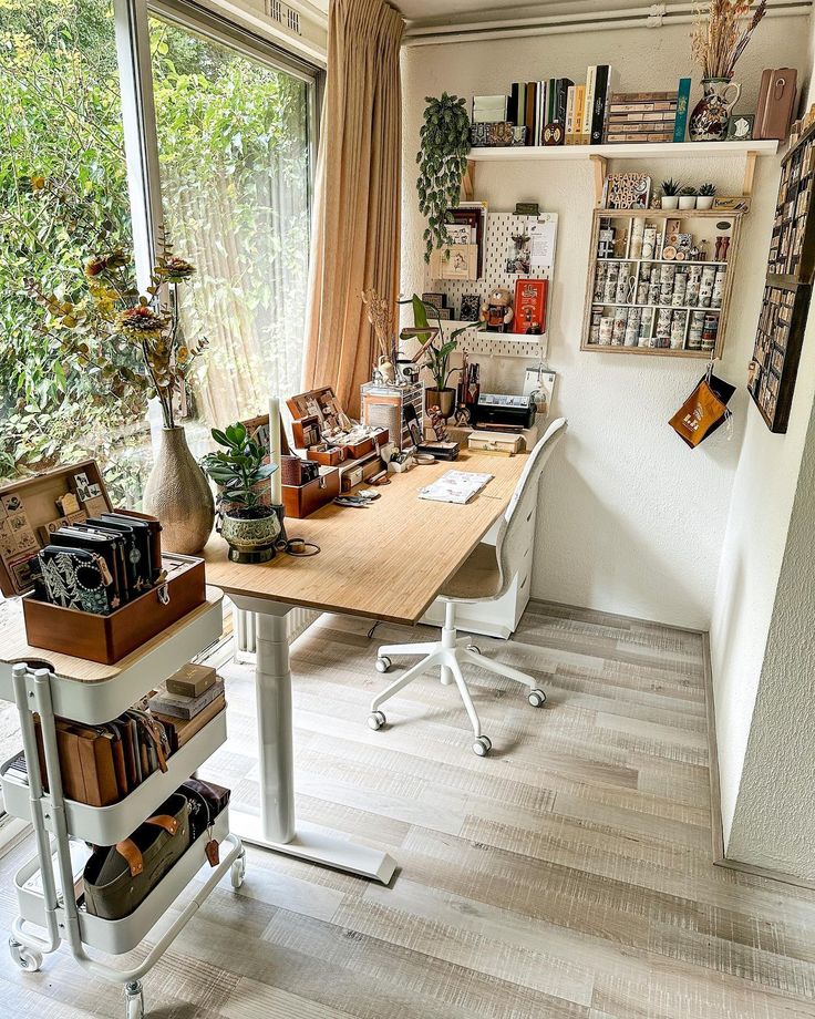 a home office with lots of books on the desk and shelves full of books in front of large windows