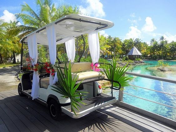 a white golf cart parked on top of a wooden deck next to a body of water