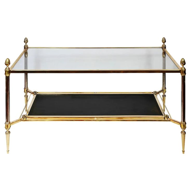 a gold and black glass coffee table with two shelves on each side, one shelf holding a