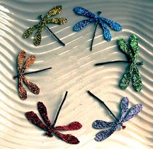 six dragonflys are arranged in a circle on a white plate with silver and green glitter