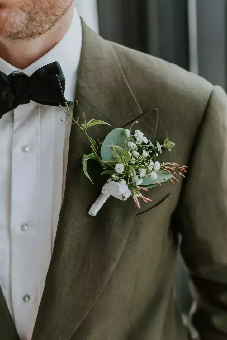 a man wearing a suit and bow tie with flowers in his lapel flower bouquet