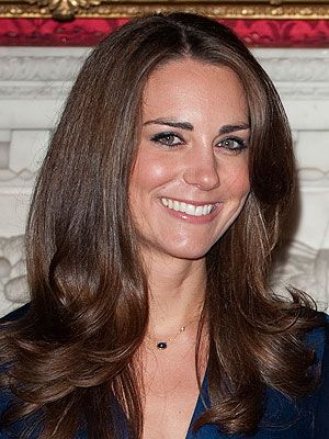 a woman with long brown hair wearing a blue blazer and smiling at the camera