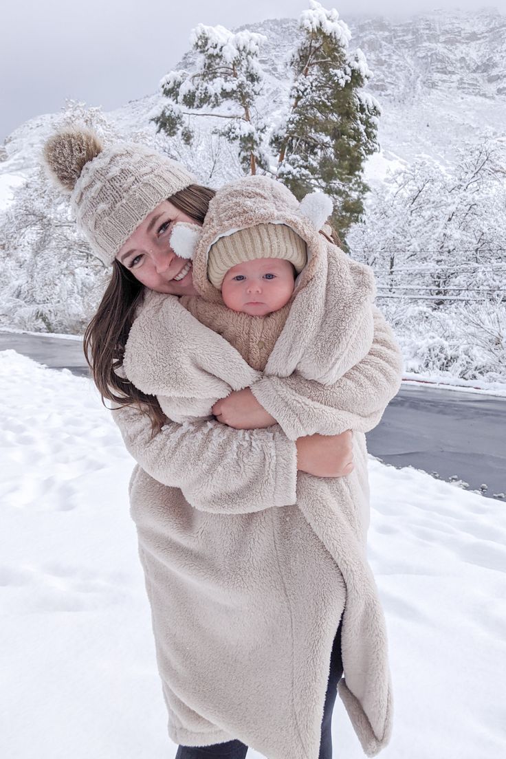 a woman holding a baby in the snow