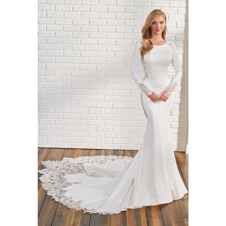 a woman in a white wedding dress standing on a wooden floor next to a brick wall