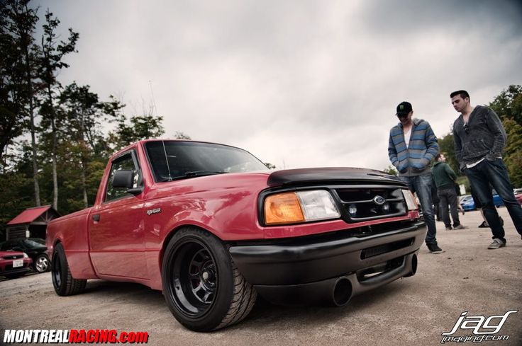 two men standing next to a red truck