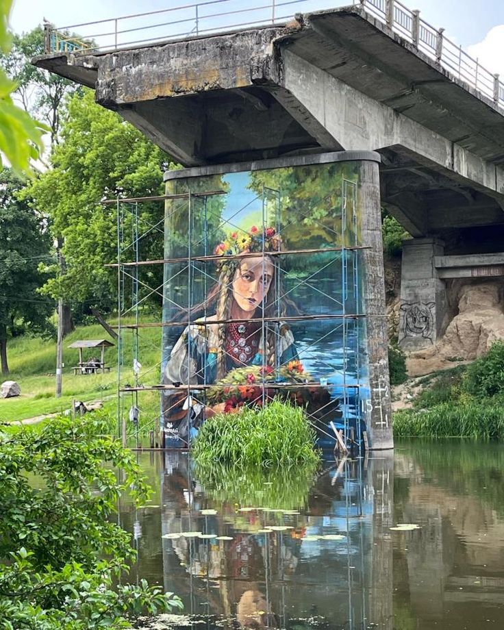 a painting on the side of a bridge with a woman holding flowers in her hands