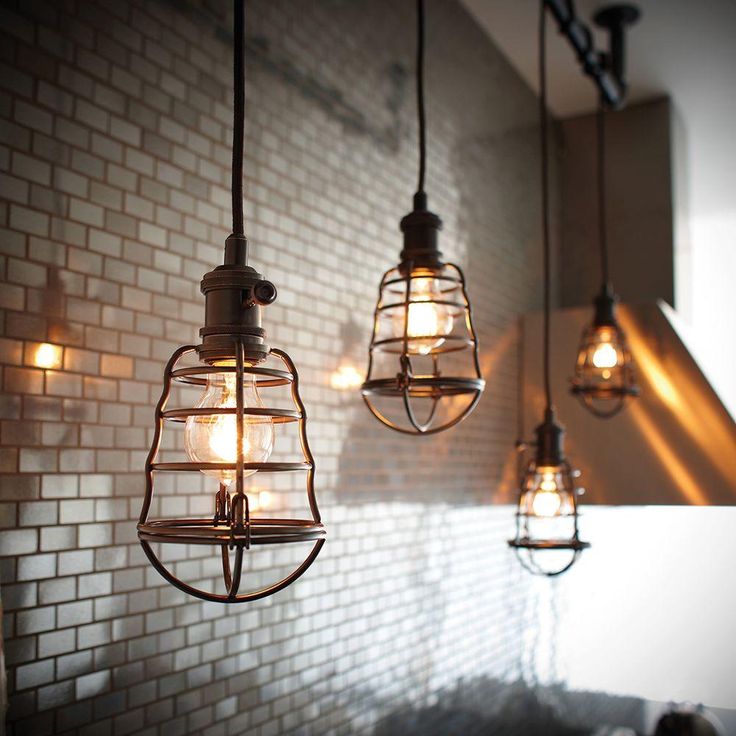 three light fixtures hanging from a brick wall in a room with white tile walls and flooring