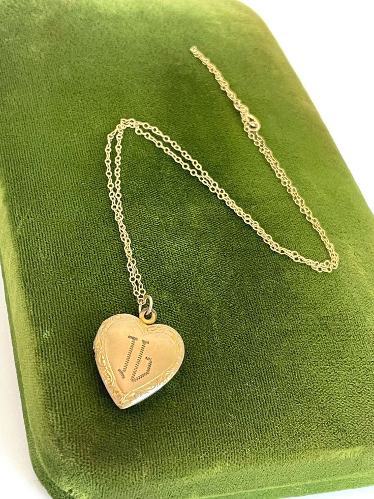 Description: Beautiful and classic vintage 12k gold  filled etched heart locket necklace. The heart pendant features intricate etched flower designs around the outside front with the initials IG monogrammed on the front.  The back of the locket is plain with no design.   The interior of the locket has two photo compartments. We have attached the locket to a delicate and dainty 14k gold filled chain which secures with a spring ring clasp. Beautiful piece of romantic antique/vintage jewelry, circa 1940s. This locket closes with a snap.  Measures:  Chain: Approx. 18'' long. Locket (with bail): 1''   Without bail: approx. 7/8''.  7/8'' wide. Weighs:   - 3.6 grams (locket with chain), 3.2 grams locket alone. Condition: In nice vintage condition.  Some light use marks here and there. See photos Vintage 14k Gold Locket Necklace, Vintage 14k Gold Locket Necklace Stamped 14k, Personalized Vintage Heart Necklace For Valentine's Day, Vintage Heart Necklace With Vintage Charm For Anniversary, Vintage Heart Necklace With Charm For Anniversary, Vintage Personalized Heart Pendant Necklace, Victorian Gold Jewelry For Anniversary Gift, Vintage Personalized Heart Necklace Keepsake, Personalized Vintage Heart Necklace Keepsake