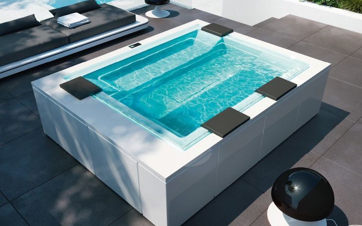 an outdoor jacuzzi is sitting on the ground next to a couch and table