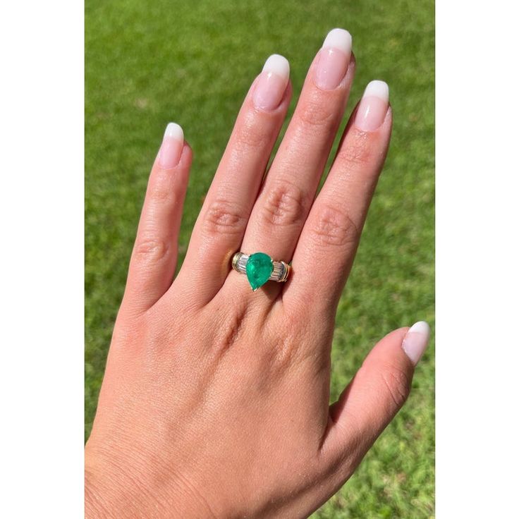 This ring presents a sophisticated blend of elegance and luxury, showcasing a 3.22 carat pear-shaped natural Colombian emerald center stone. Adorned with 0.66 CTTW in baguette-cut diamond side stones. The center stone is set in a 3-prong setting with an open back, allowing the emeralds vivid green hue to radiate brilliantly and securely.   Item Details: - Type: Ring  - Metal: 18K Yellow Gold  - Weight: 8.0 Grams  - Setting: 3-Prong  - Size: 7 (adjustable)  Emerald Details: - Carat: 3.22  - Cut: Luxury Pear-shaped Emerald Ring With Prong Setting, Luxury Pear-shaped Brilliant Cut Emerald Ring, Elegant Pear-shaped Emerald Ring With Prong Setting, Pear-shaped Brilliant Cut Green Emerald Ring, Pear-shaped Brilliant Cut Emerald Ring, Elegant Pear-shaped Prong Set Emerald Ring, Elegant Pear-shaped Green Emerald Ring, Green Pear-shaped Brilliant Cut Emerald Ring, Elegant Green Pear-shaped Emerald Ring