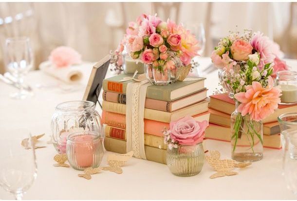 three vases filled with pink flowers sitting on top of books next to each other