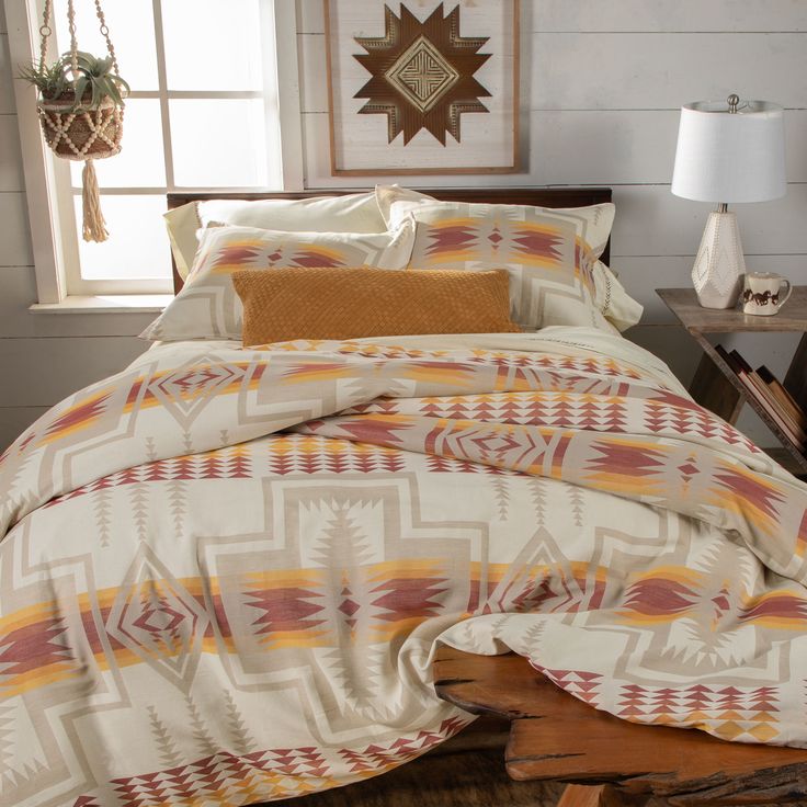 a bed with an orange and white comforter next to a wooden table in a room