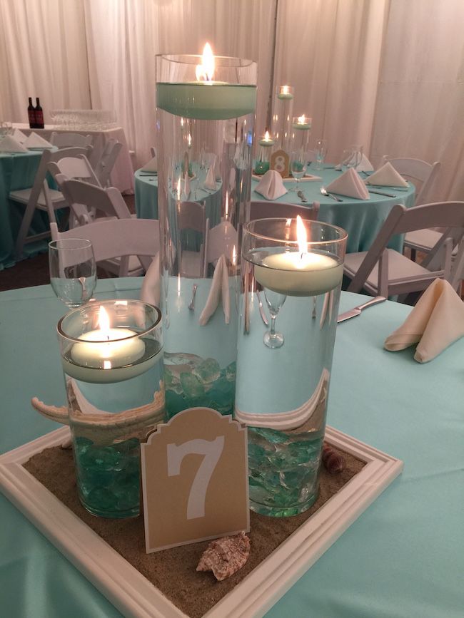 there are candles that are on the table in front of the centerpiece and place cards