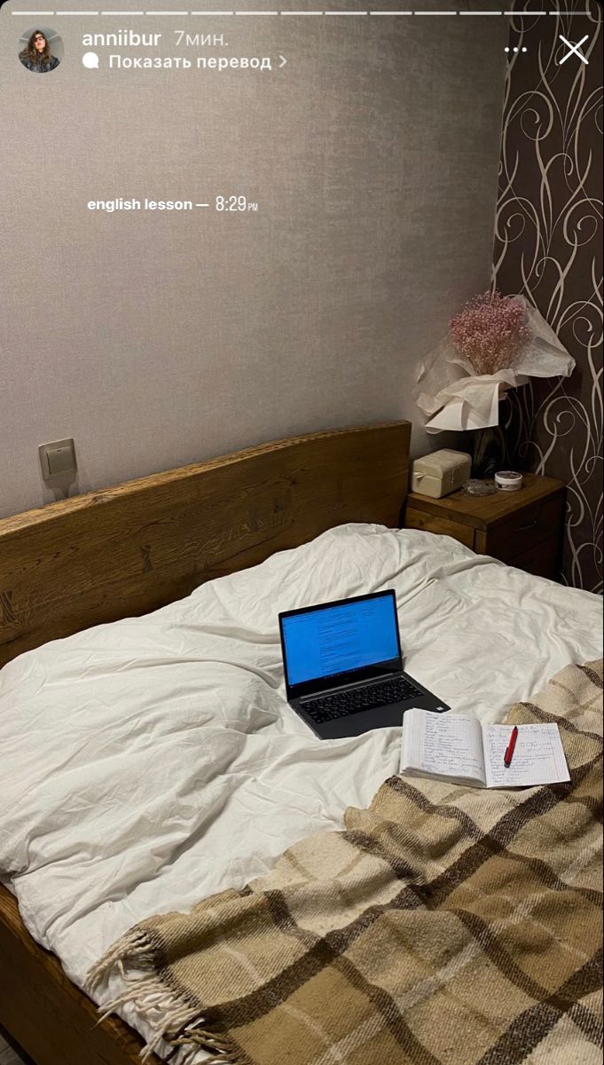 an open laptop computer sitting on top of a bed next to a notebook and pen