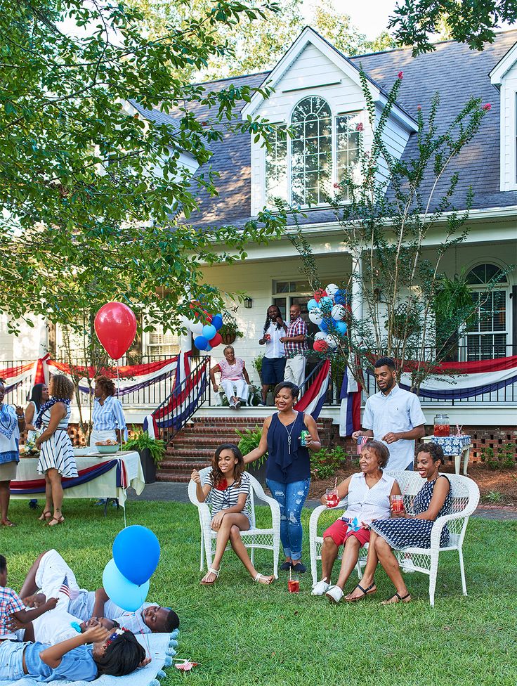 a group of people sitting on lawn chairs in front of a house with balloons and streamers