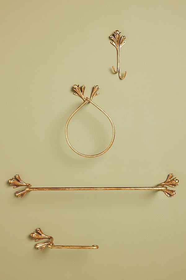 two gold - plated objects are displayed on a beige background, including an arrow