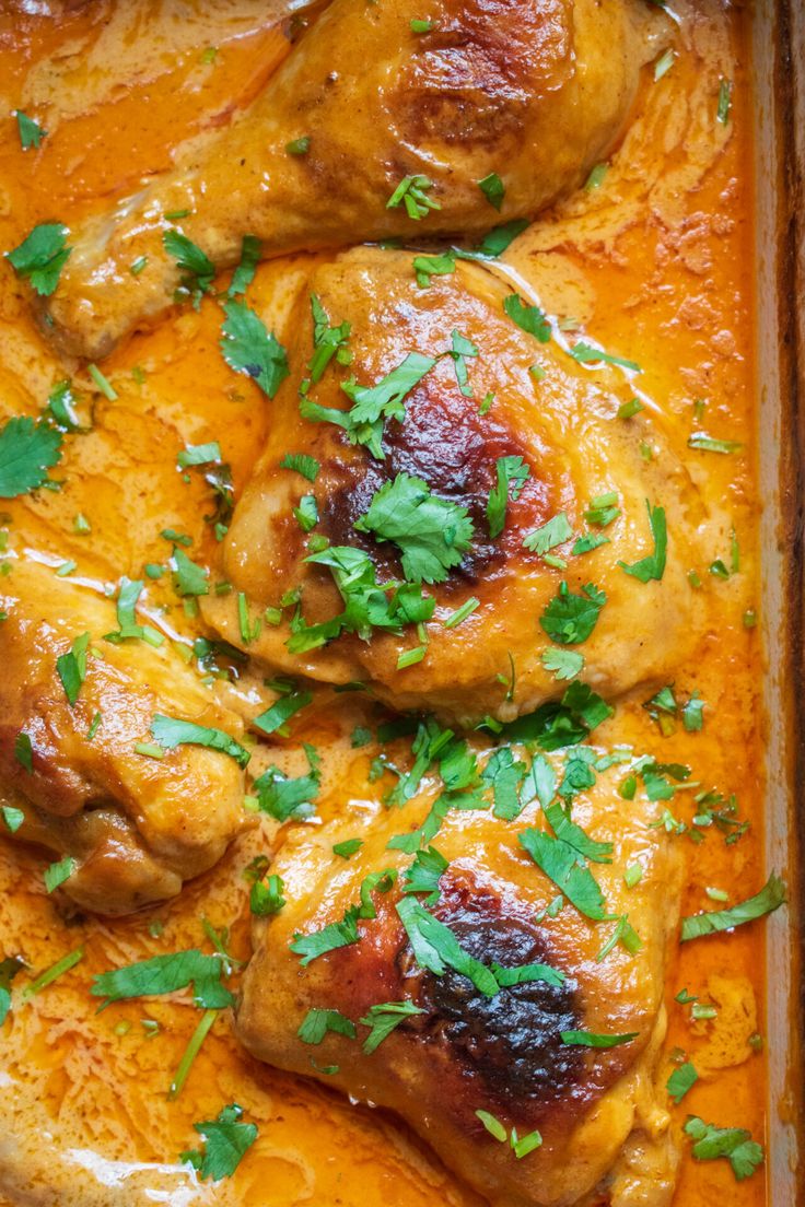 chicken with orange sauce and parsley in a casserole dish